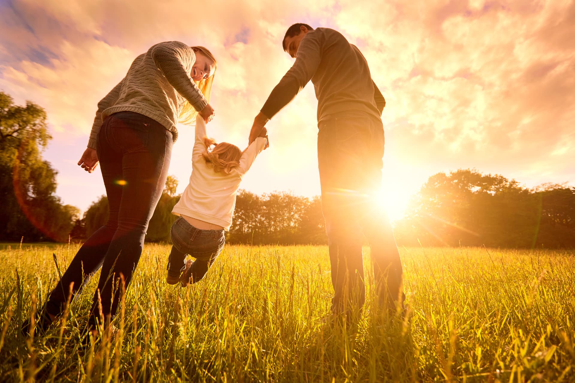 Family playing in a field at sunset